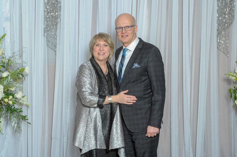 Elegantly dressed couple posing in front of a silver draped backdrop at a Halifax gala photo booth by Moments in Time Photography Studio
