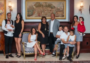 Mother and father with their children and grandchildren, posing together in the living room of their home. The family is captured in a warm and intimate moment, surrounded by the cozy setting of their house.