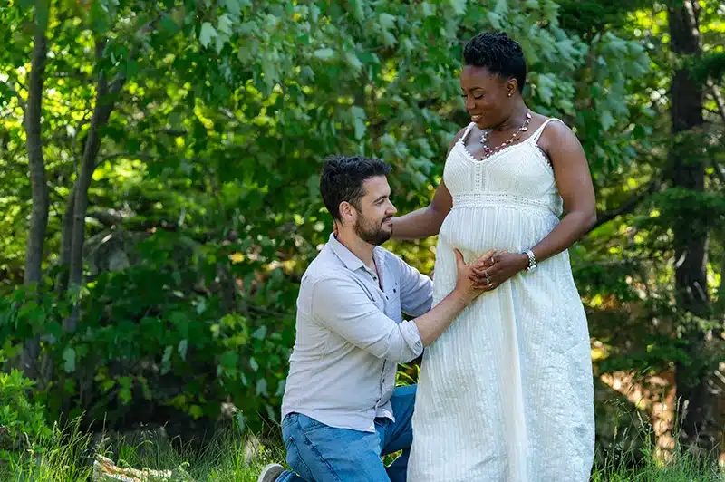 Maternity photo with dad on his knees looking at mom's belly. Taken outside of our studio in Halifax
