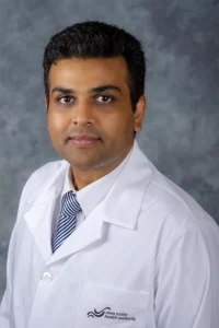 A professional headshot of a Nova Scotia Health worker wearing a doctor's robe. The individual is dressed in full medical attire, with a confident and compassionate expression, captured against a neutral background, reflecting professionalism and dedication in their healthcare role.