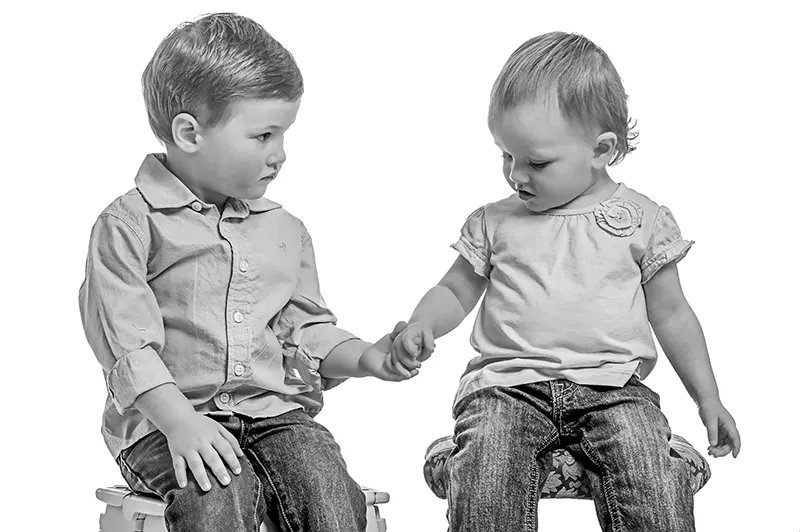 Black and white studio portrait of young brother and sister holding hands at Moments in Time Photography Studio Halifax