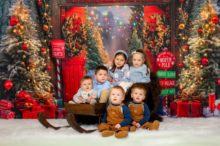 Christmas mini portrait sessions Halifax Nova Scotia 6 Group of six young children in blue and brown outfits with a wooden sleigh at a North Pole Christmas backdrop, Halifax