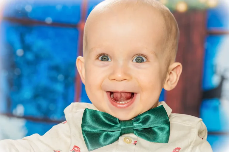Christmas mini portrait sessions Halifax Nova Scotia 4 Laughing baby boy in a green satin bow tie against a blue winter window backdrop, Halifax Christmas mini session