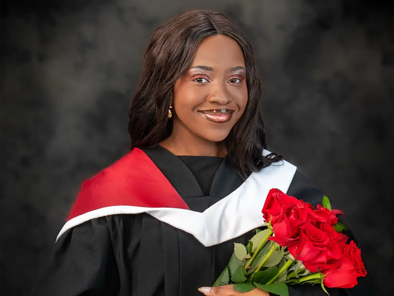 Halifax Photographers & Photography Studio 1 Smiling graduate in black gown with red and white hood holding red roses for a professional graduation portrait in Halifax, NS