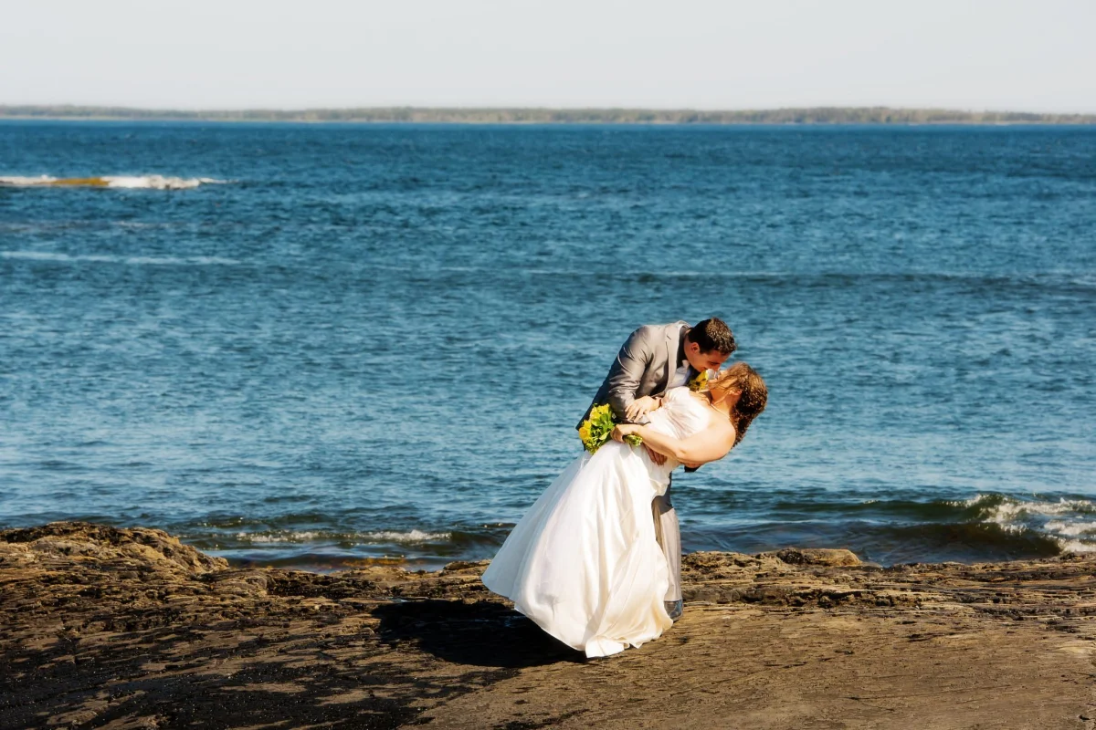 Wedding Photography 7 Groom dipping his bride for a kiss on a rocky Nova Scotia shoreline with the ocean behind them, Halifax wedding photography