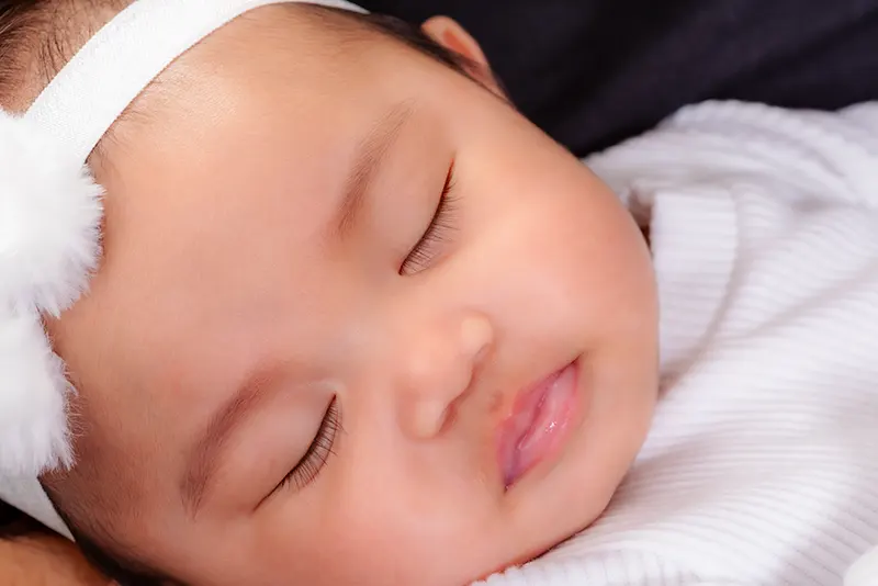 sleeping newborn baby girl white headband portrait
